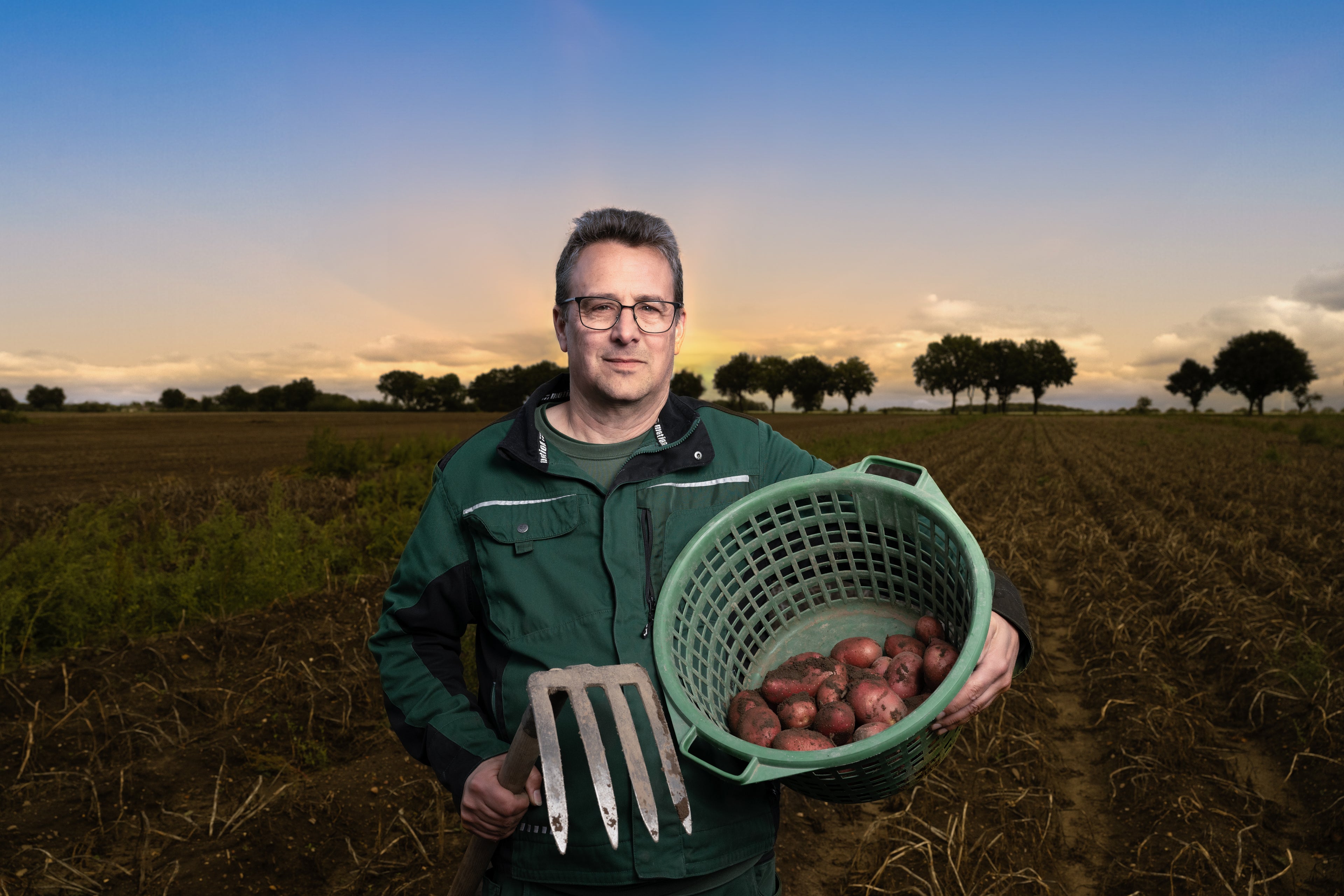 Frederik Lenz vom Hof Lenz mit frisch geernteten roten Kartoffeln auf dem Acker bei Sonnenuntergang