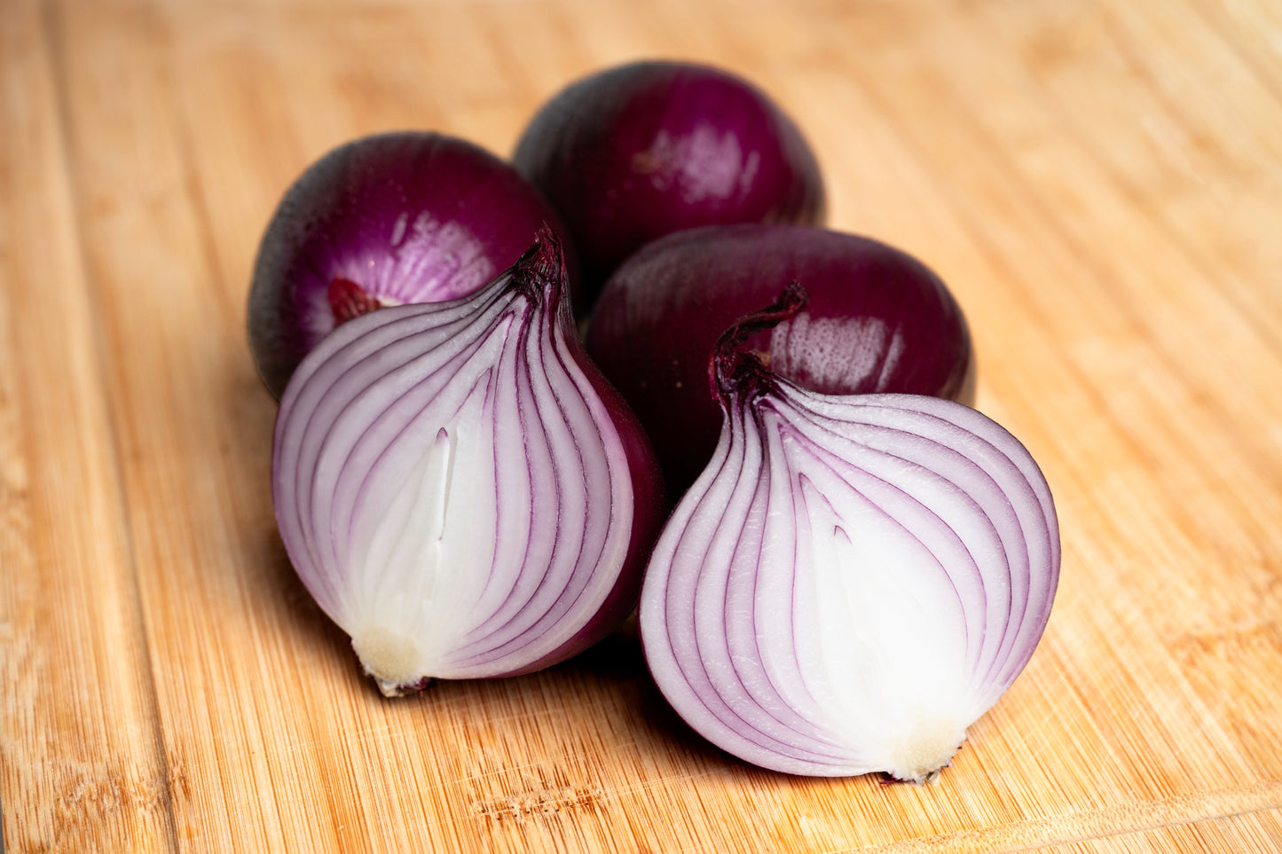 Frisch aufgeschnittene Red Tide Zwiebeln vom Hof Lenz auf Holzbrett – violett-weißes Zwiebelinnere, aromatisch und kräftig im Geschmack.