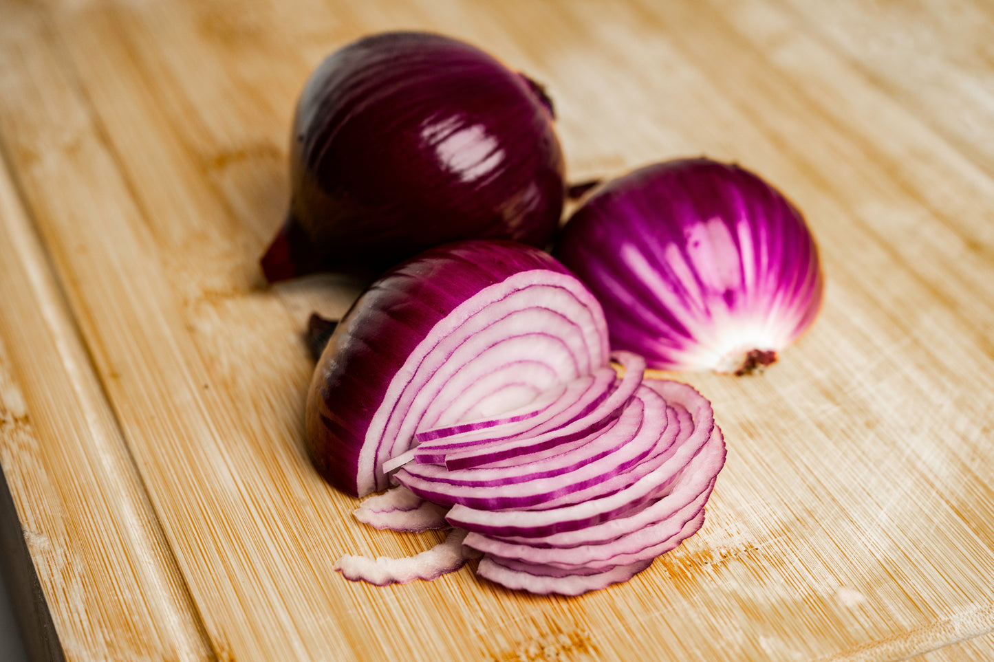 Fein geschnittene Red Tide Zwiebeln vom Hof Lenz auf Holzbrett – aromatisch, frisch und ideal für Salate, Chutneys oder zum Fermentieren.